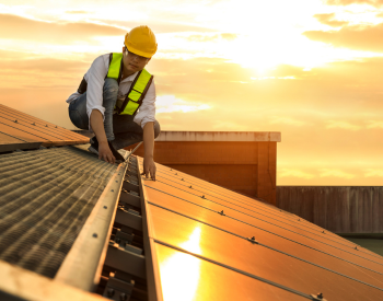 Technician inspecting rooftop solar installation in River Oaks